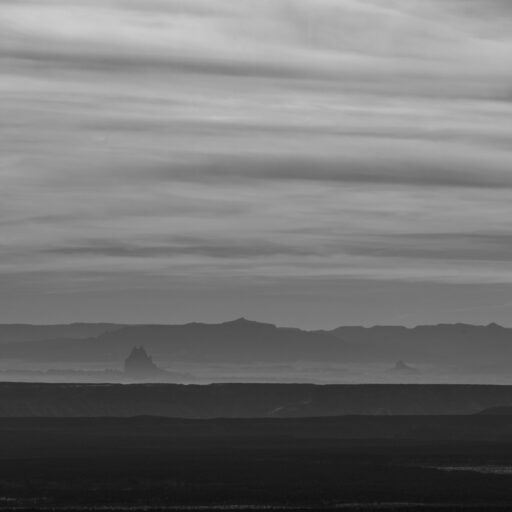 Black-and-white desert ridgelines layered beneath a streaked sky