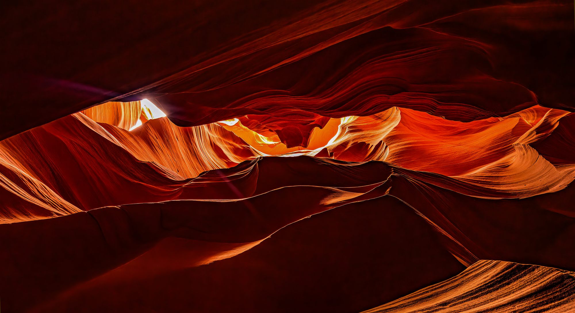 Waves of red and amber sandstone inside a slot canyon, lit from above