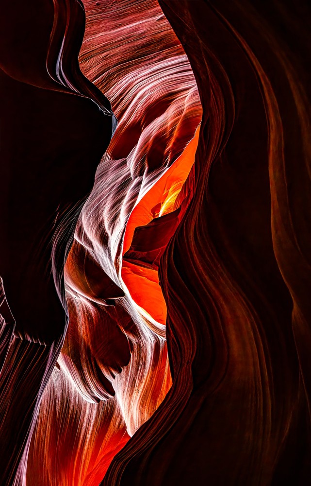 Abstract slot canyon of striated curving sandstone in dark red and mauve, a bright molten-orange opening glowing at the center