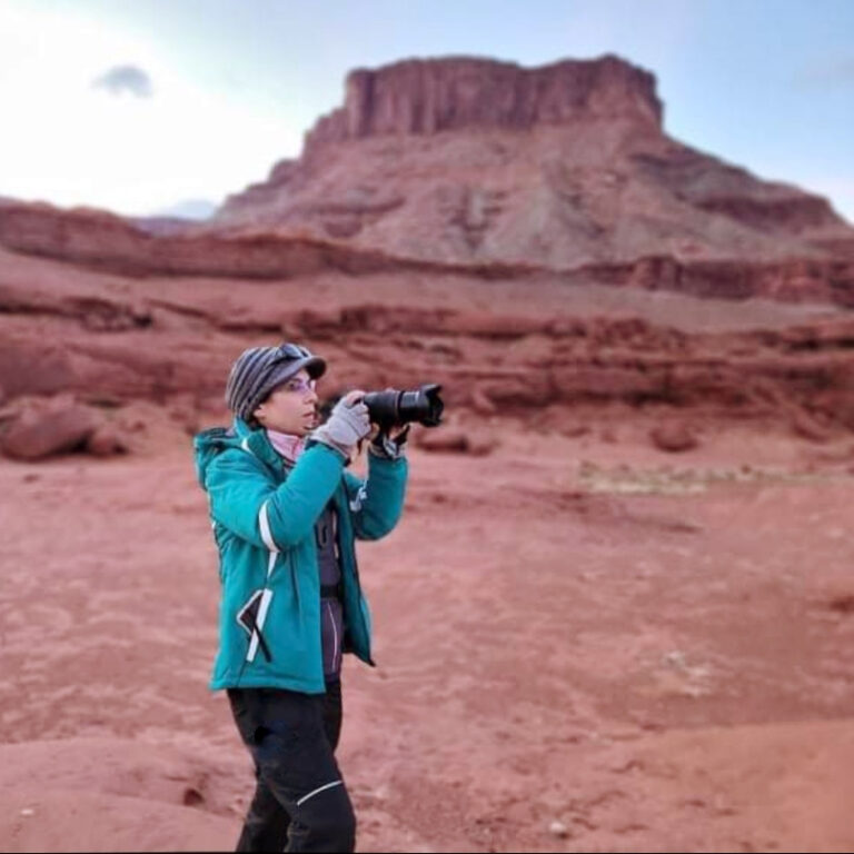 Marina standing in a red-rock desert, camera raised to her eye
